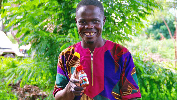 Robert, a borrower in Uganda, holding his chili powder product