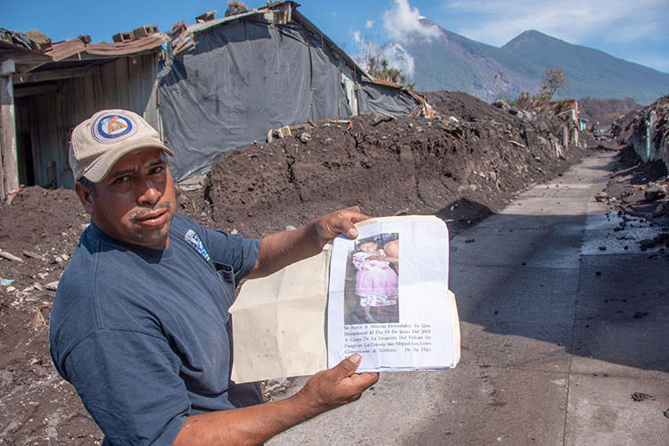 Picture of man in Guatemala and volcano Fuego smoking in distance