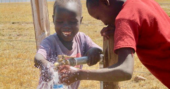 Child in Africa enjoying safe drinking water