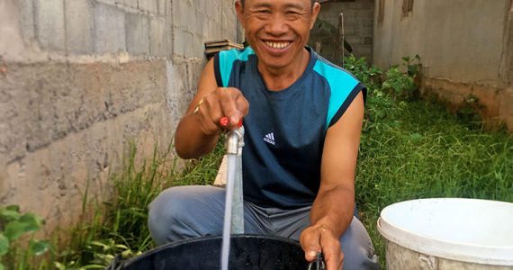 Picture of pastor with well in front of house church