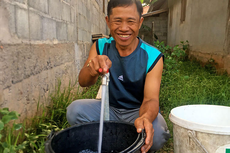 Picture of pastor with well in front of house church