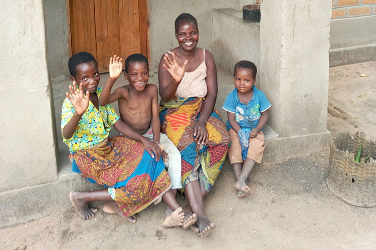 Picture of family in Malawi with house provided by Disaster Relief Ministry