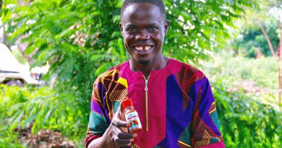 Robert, a borrower in Uganda, holding his chili powder product