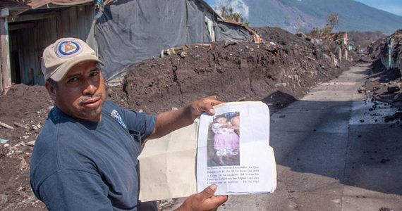 Picture of man in Guatemala and volcano Fuego smoking in distance