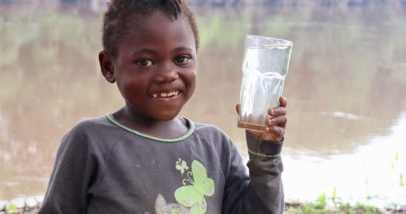 Picture of girl in Cameroon holding glass of safe water